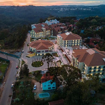 Buona Vitta Gramado Resort & Spa By Gramado Parks ภายนอก รูปภาพ The photo shows an aerial view of a hotel complex set in a hilly, wooded area. The buildings feature a mix of architectural styles with several structures, including a central round pavilion. Surrounding the buildings are well-maintained gardens and 
