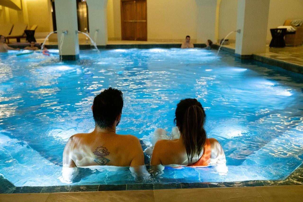 Buona Vitta Gramado Resort & Spa By Gramado Parks ภายนอก รูปภาพ The photo shows a couple sitting in a swimming pool with gentle lighting. They are facing away from the camera, appearing relaxed and enjoying their time together. The water is illuminated with a soft blue light, creating a serene atmosphere. In the 