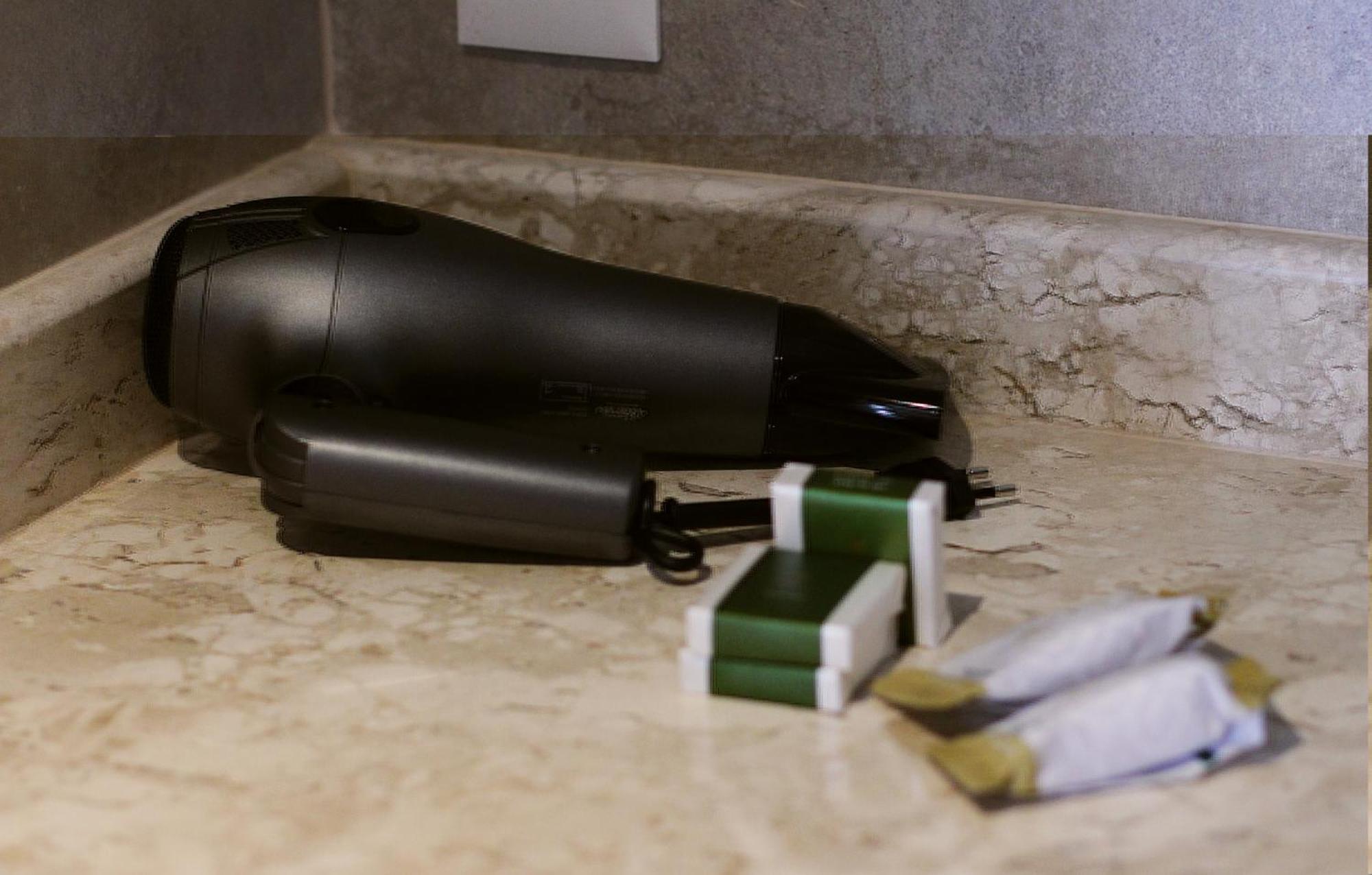 Buona Vitta Gramado Resort & Spa By Gramado Parks ภายนอก รูปภาพ The photo shows a black hairdryer placed on a marble countertop. Next to the hairdryer, there are two wrapped items, likely toiletries, with green and white packaging. Additionally, there are two more items, also wrapped, which appear to be in simila