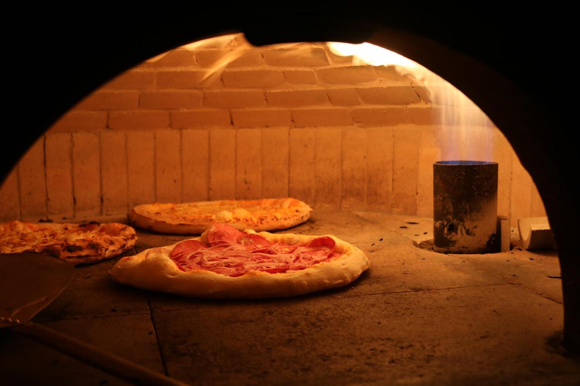 Buona Vitta Gramado Resort & Spa By Gramado Parks ภายนอก รูปภาพ The photo shows a traditional pizza oven. Inside the oven, there are several pizzas placed on the stone surface. The pizzas appear to have various toppings, including what looks like cheese and possibly pepperoni. The oven has a warm, glowing ambianc
