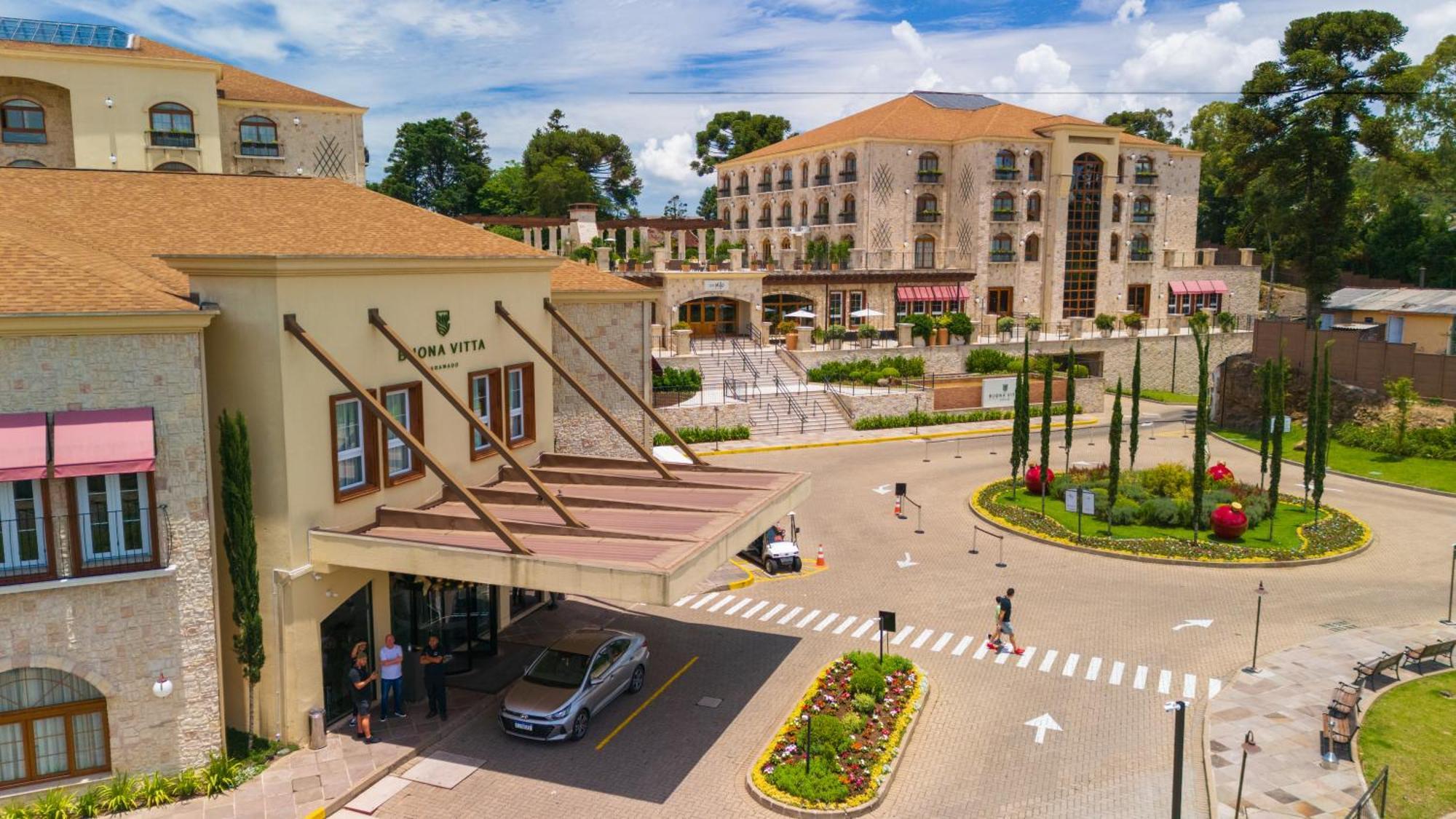 Buona Vitta Gramado Resort & Spa By Gramado Parks ภายนอก รูปภาพ The photo shows a luxurious hotel or resort entrance, featuring a modern yet elegant architectural design. In the foreground, there is a covered entrance where vehicles are likely dropping off guests. The building has a stone facade and a welcoming e